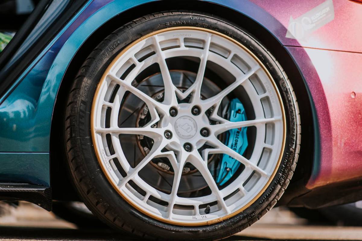 Close-up of a vibrant car wheel featuring a multi-spoke white rim, blue brake caliper, and performance tire.
