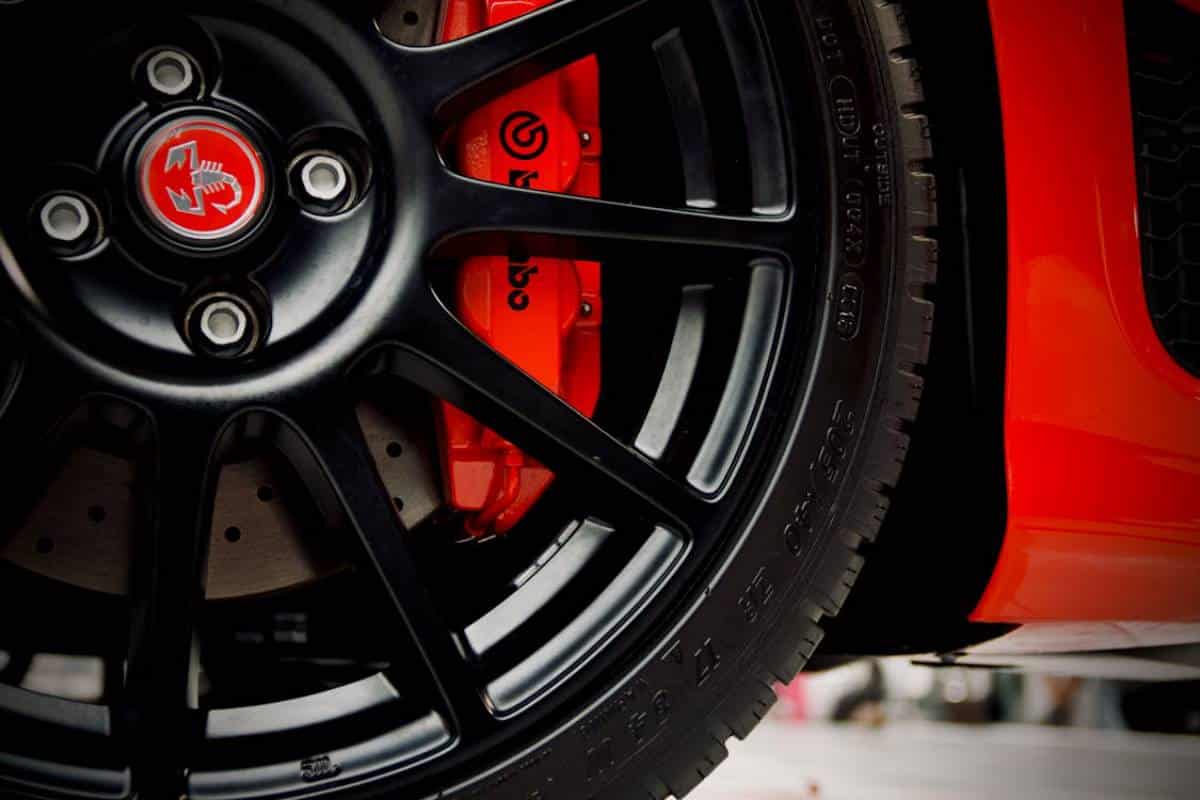 Close-up of a black alloy wheel featuring a red brake caliper.