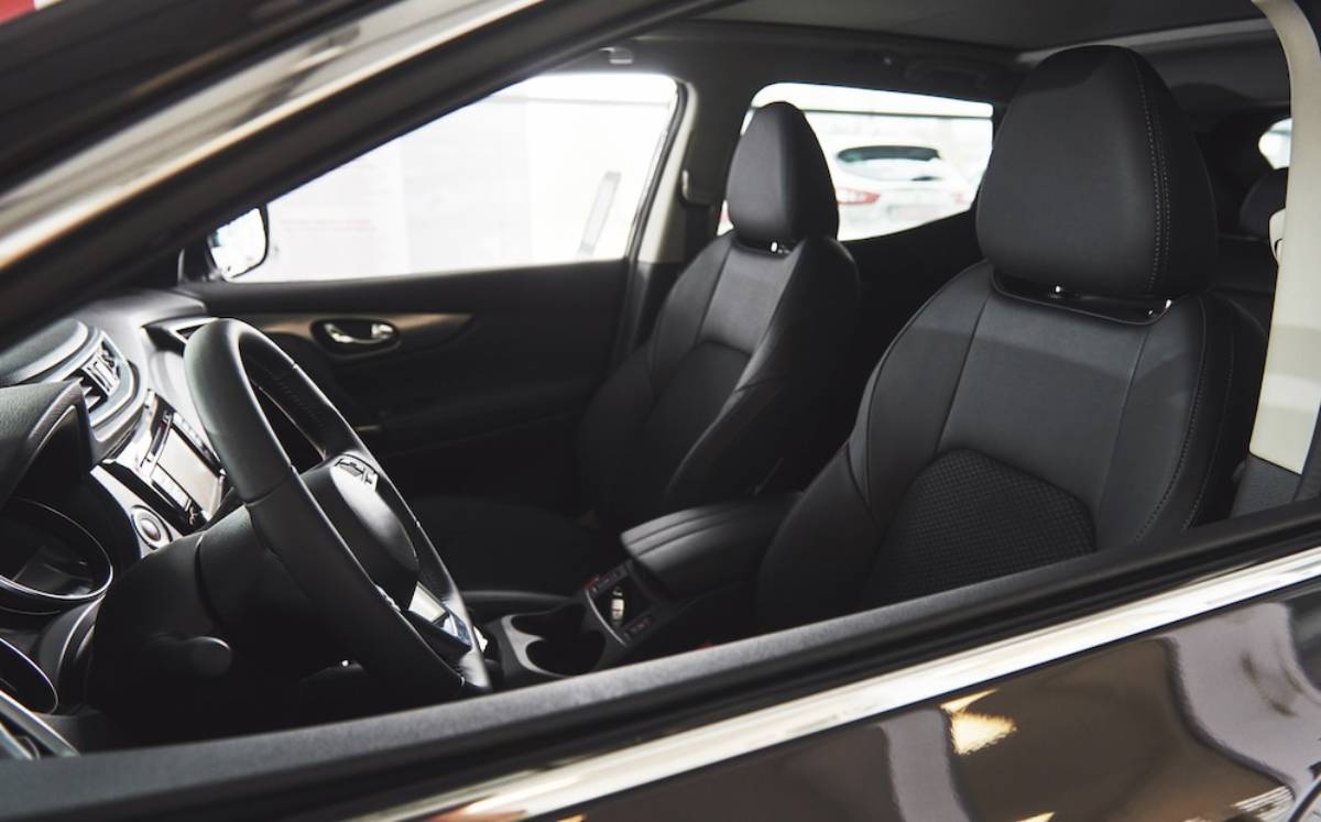 A modern car interior featuring black fabric seats, steering wheel, and dashboard, showcasing a spacious and sleek design.