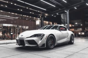 A sleek white Toyota Supra parked stylishly under modern lighting in an urban setting.