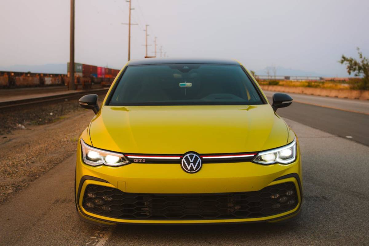 Front view of a vibrant yellow Volkswagen GTI parked on a deserted road.