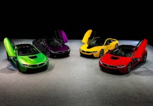 Four BMW i8 sports cars in vibrant colors—green, purple, yellow, and red—displayed with doors open against a dark background.