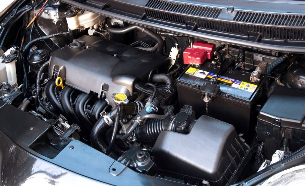 A car engine bay featuring a clean engine block, battery, and various components, with visible hoses and wiring.