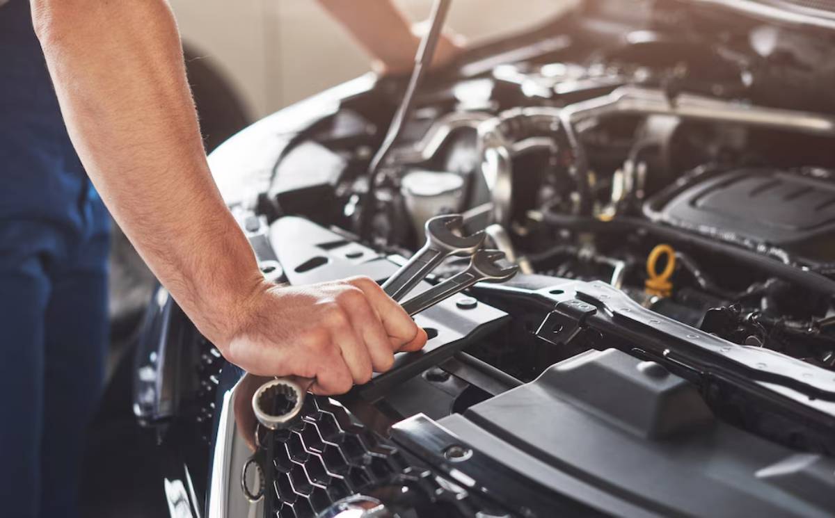  Mechanic using wrench on a car engine in a workshop.